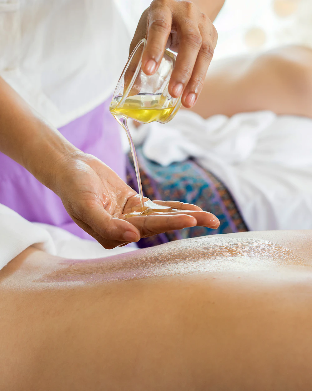 Therapist pouring warm massage oil during a session at a massage studio in Arlington, TX